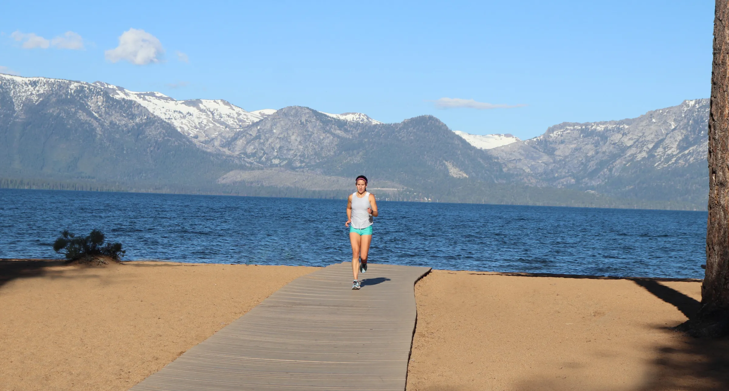 An open trail toward the mountains and a lake.